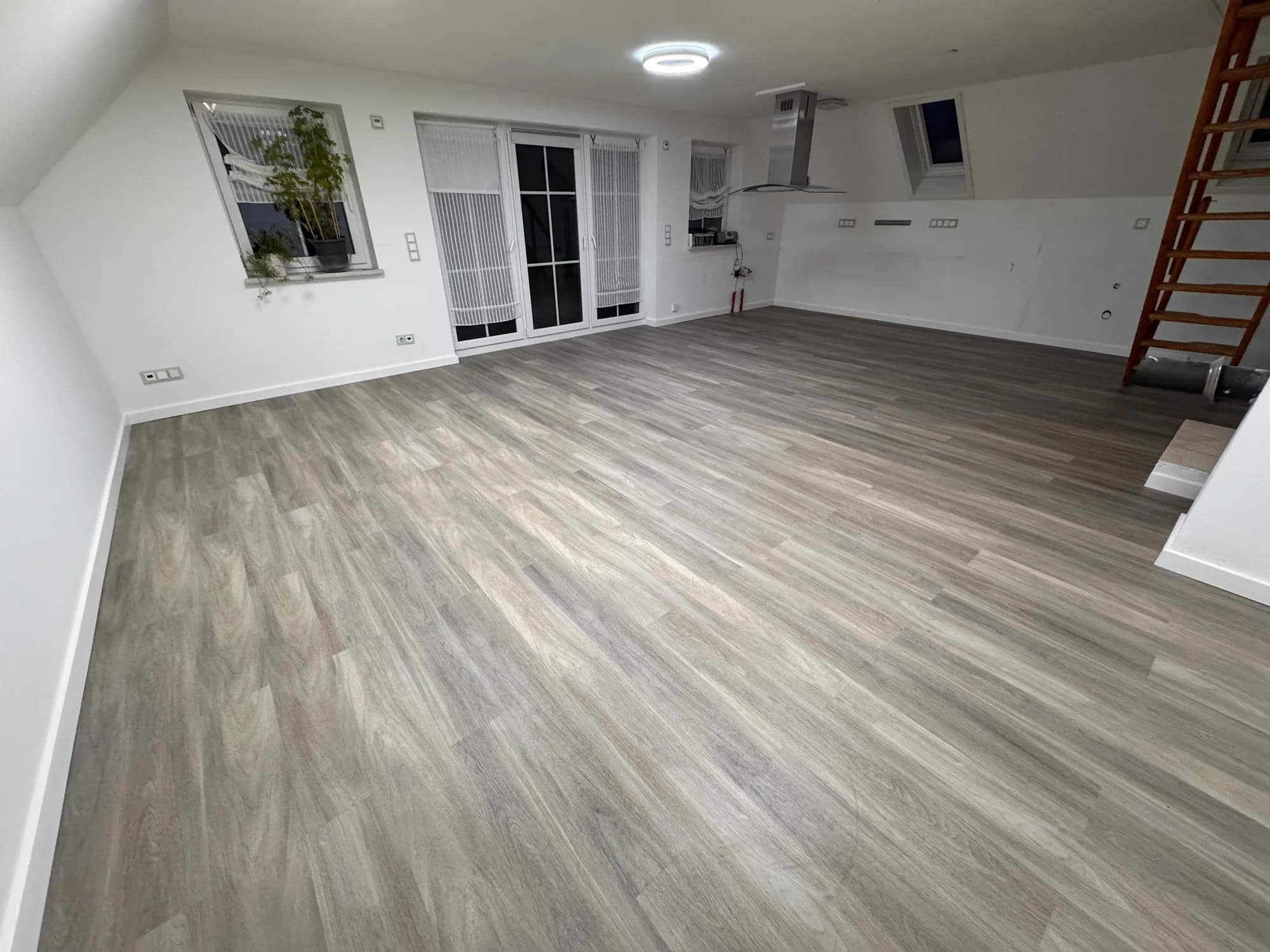 Großer Wohnraum unter dem Dach mit neuem Boden in grauer Holzoptik